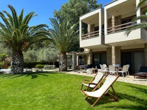 a couple of chairs sitting on the grass in front of a house at Escape to Paradise Experience Luxury and Serenity at Villa Elina in Sithonia in Metókhion Ayías Kiriakís