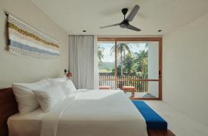 1 dormitorio con cama blanca y balcón en Boni Beach Lombok Boutique Hotel, en Selong Belanak