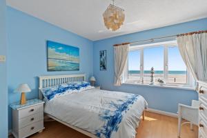 ein blaues Schlafzimmer mit einem Bett und einem Fenster in der Unterkunft Strand Cottage - Direct Beach Access in Saundersfoot