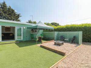 a green house with a table and a tent at Foxes Den in Ferndown