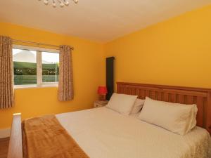a bedroom with a bed with yellow walls and a window at Foxes Den in Ferndown