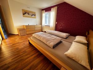 - une chambre avec 2 lits et un mur rouge dans l'établissement Ferienwohnung zum Lösershag, à Wildflecken