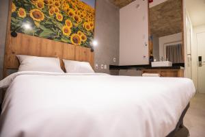 a bedroom with a white bed and a painting of sunflowers at CAMPOS DE HOLAMBRA INN in Paranapanema