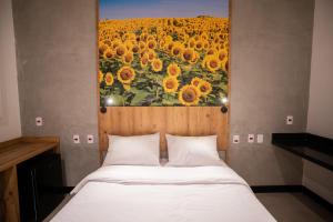 uma cama com uma pintura de um campo de girassóis em CAMPOS DE HOLAMBRA INN em Paranapanema