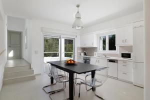 a white kitchen with a black table and chairs at Villa Levanda by WhiteDream Villas in Kassiopi