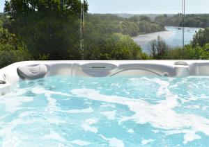 a jacuzzi tub with a view of a river at Gwbert Holiday Cottages, Green Meadow in Cardigan
