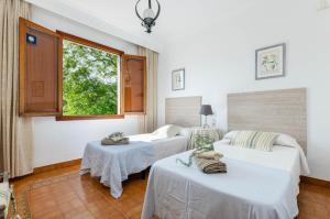 two beds in a room with a window at YourHouse Can Marquesi in Lluc