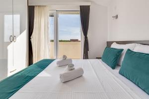 a bedroom with a large white bed with towels on it at Apartman Strmota s bazenom i jakuzijem in Sveti Filip i Jakov