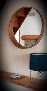 a mirror on a wall with a table and a blue chair at La Louronnaise in Bordères-Louron