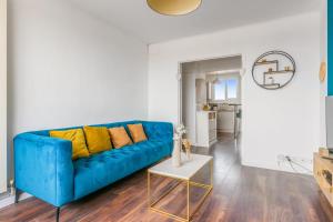 un sofá azul con almohadas amarillas en la sala de estar. en Modern and colourful apartment with balcony - Montpellier - Welkeys, en Montpellier