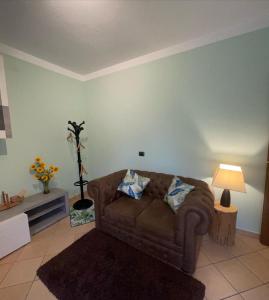 sala de estar con sofá marrón y lámpara en Casa Iris, en Omegna