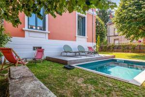 un patio trasero con piscina, sillas y una casa en Villa with pool and garden close to Lyon - Welkeys, en Champagne-au-Mont-d'Or