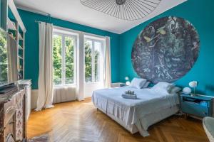 une chambre bleue avec un lit et un grand tableau sur le mur dans l'établissement Villa with pool and garden close to Lyon - Welkeys, à Champagne-au-Mont-dʼOr