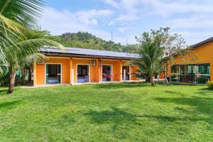 an orange building with palm trees in front of it at Pousada Villa Piemonte in Ubatuba
