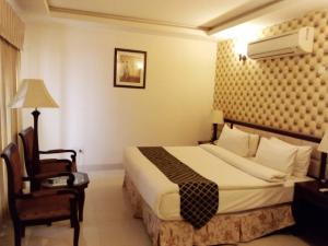 una camera d'albergo con letto e sedia di Royal Desert Palm Hotel a Rahimyar Khan