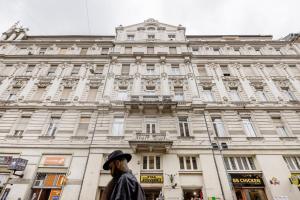 Un uomo con un cappello davanti a un palazzo di Elegant Apartment in Super Central Location a Budapest