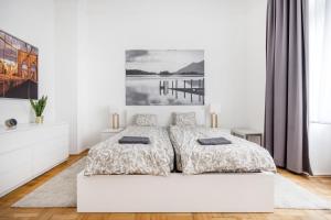 a white bedroom with a bed and a painting on the wall at Elegant Apartment in Super Central Location in Budapest