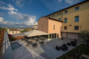 een patio met tafels en stoelen en een gebouw bij Hotel Palazzo San Lorenzo & Spa in Colle di Val d'Elsa