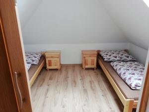 two beds in a room with wooden floors at Chyžka Stará Hora in Sebechleby