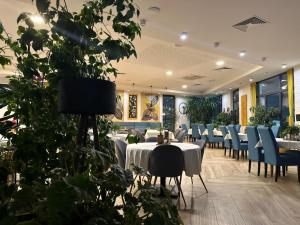 a dining room with tables and chairs and plants at Apartmani Leburic in Prnjavor