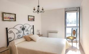 a white bedroom with a large bed and a chandelier at El rincón del 12 in Pontevedra