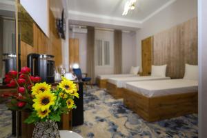 a hotel room with two beds and a vase of flowers at Almaty City in Türkistan