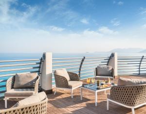 a balcony with chairs and a table and the ocean at Grand Hotel Pietra Ligure in Pietra Ligure