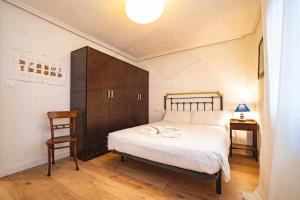 a bedroom with a large bed and a wooden cabinet at La Capilla Apartamento in Oviedo