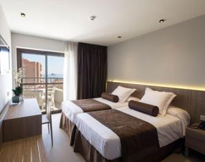 a hotel room with two beds and a balcony at Hotel Acapulco Benidorm in Benidorm