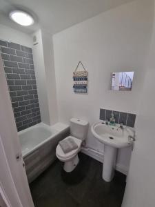 a bathroom with a toilet and a sink and a bath tub at The Cottage @ St Margarets in Ryde
