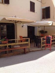 eine Außenterrasse mit Tischen, Sonnenschirmen und Stühlen in der Unterkunft Albergo Dal Fata in Gambassi Terme