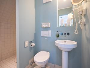 a bathroom with a white toilet and a sink at The New Yorker Hotel Köln-Messe in Cologne
