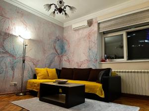 a living room with a yellow couch and a colorful wall at Apartman Sasha 1 in Sajmište