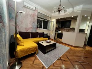 sala de estar con sofá amarillo y mesa en Apartman Sasha 1 en Sajmište
