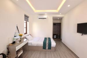 a bedroom with a bed and a desk and a tv at Rova 105 Hotel in Phu Quoc