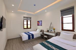 a hotel room with two beds and a desk at Rova 105 Hotel in Phu Quoc