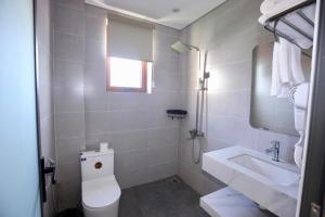 a white bathroom with a toilet and a sink at Rova 105 Hotel in Phu Quoc
