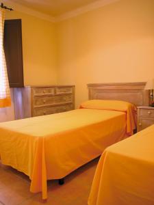two beds in a room with yellow walls at APARTAMENTS PUIG GILI in Mura