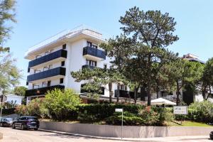 a white building with cars parked in front of it at Hotel Eden in Lignano Sabbiadoro