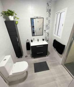 bagno con servizi igienici, lavandino e specchio di Apartamento AGUA con Jacuzzi y terraza a Las Palmas de Gran Canaria