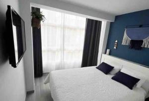 a bedroom with a white bed and a blue wall at Apartamento AGUA con Jacuzzi y terraza in Las Palmas de Gran Canaria
