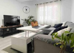 a living room with a couch and a table with a laptop at Apartamento AGUA con Jacuzzi y terraza in Las Palmas de Gran Canaria