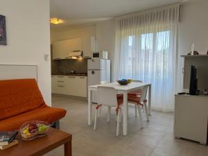 a kitchen and dining room with a white table and chairs at Villa Tre Pini in Lignano Sabbiadoro
