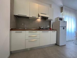 uma cozinha com armários brancos e um frigorífico em Villa Tre Pini em Lignano Sabbiadoro