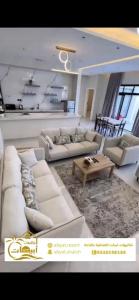 a living room with white couches and a table at شاليهات أبيات الفندقية in Al Baha