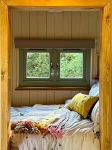 a bedroom with a bed and two windows at Secret Garden Shepherd Hut in Macclesfield