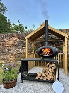 a wood fired oven with a pile of fire wood at Secret Garden Shepherd Hut in Macclesfield
