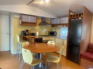 - une cuisine avec une table en bois et un réfrigérateur noir dans l'établissement Mobil home Aluna Vacances camping Sunêlia, à Ruoms