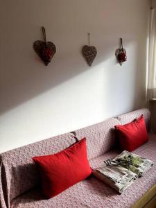 a couch with red pillows and hearts on the wall at Casa Horvais San Candido in San Candido