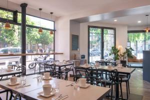 a restaurant with tables and chairs and windows at Hôtel Coypel by Magna Arbor in Paris